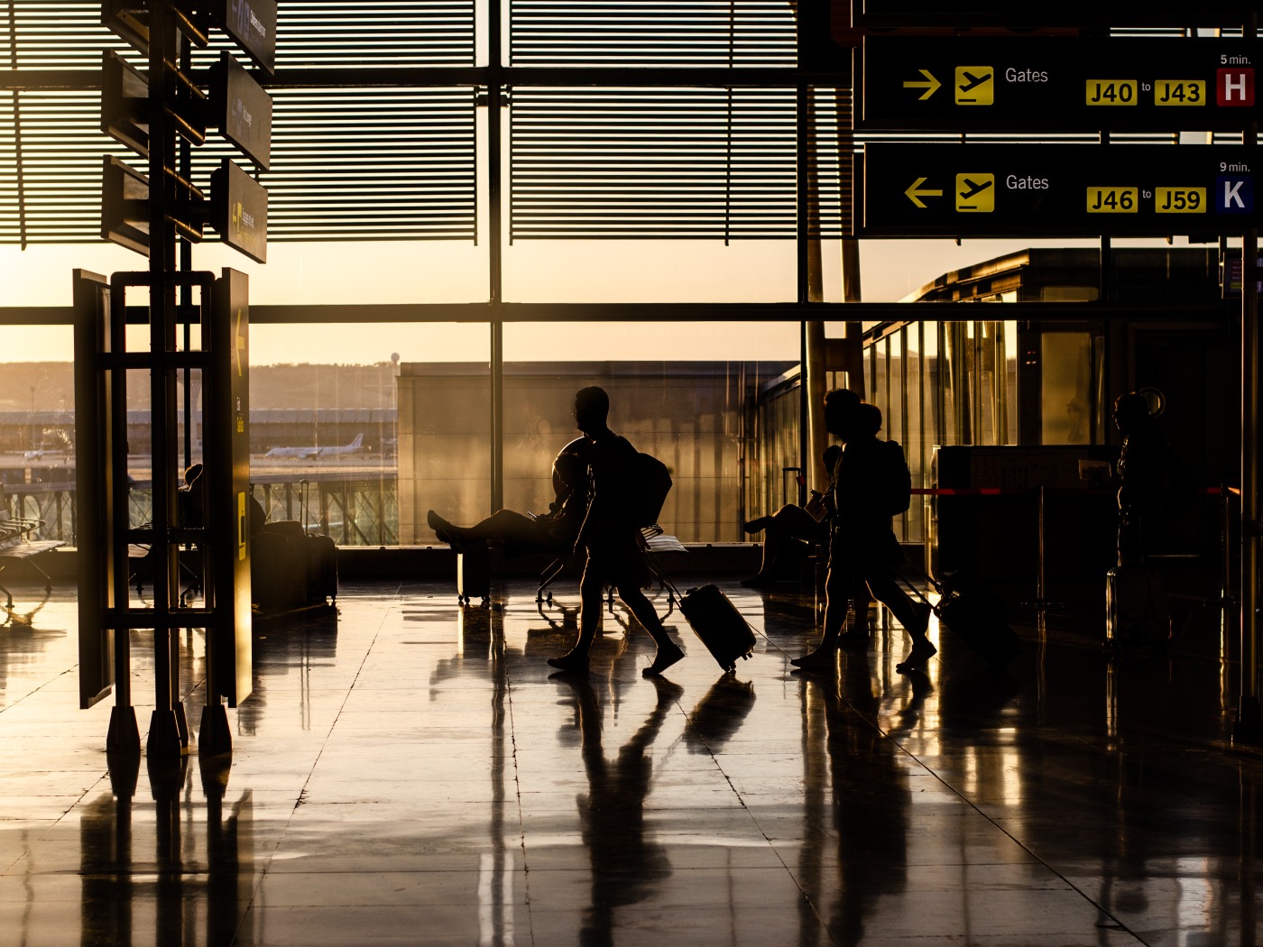 Travellers with luggage crossing an airport terminal at sunrise